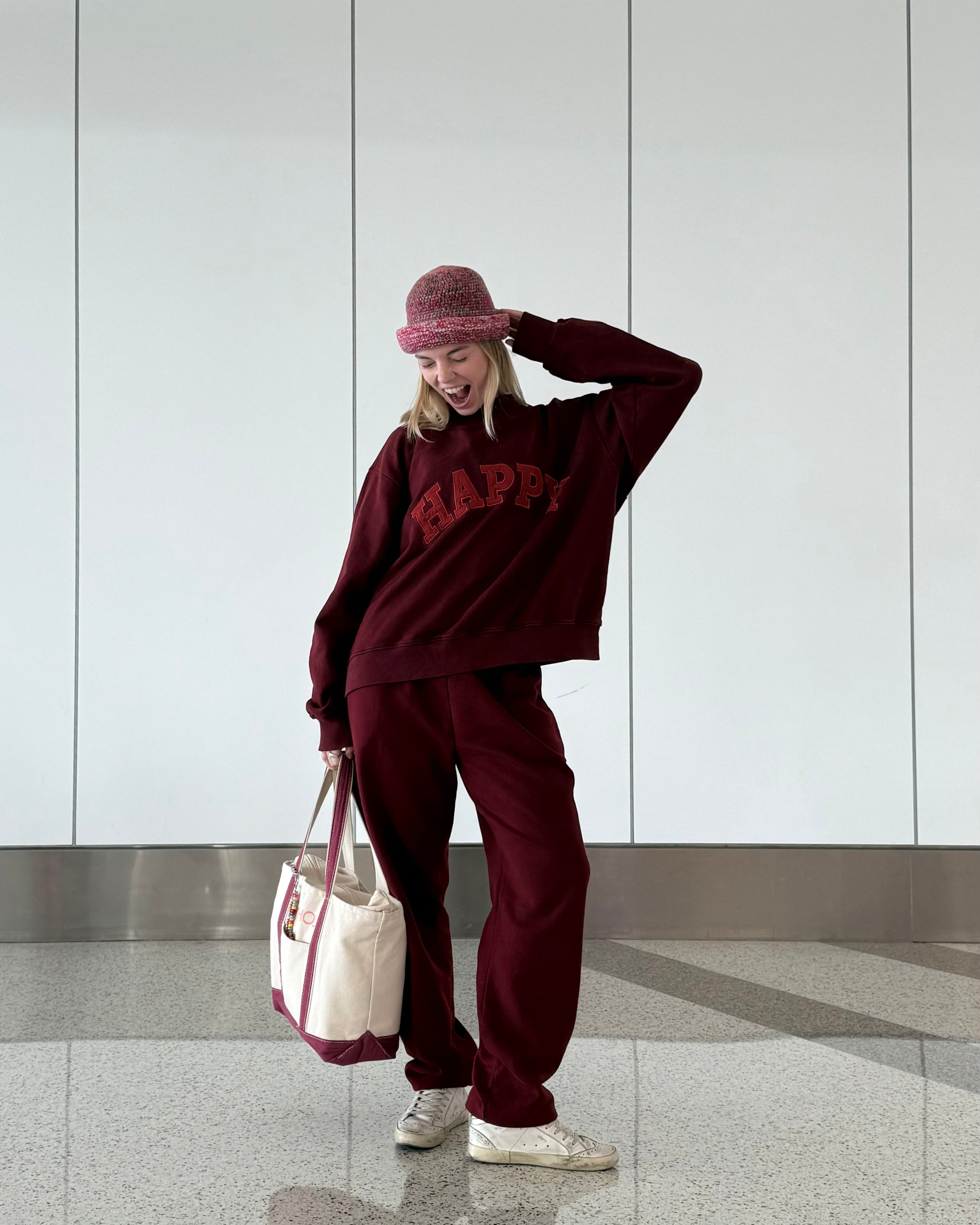 Person wearing a maroon outfit with 'HAPPY' text, travel outfit.